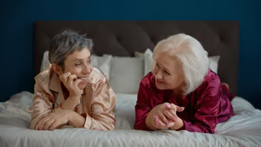 Happy laughing two elderly women enjoying time together during pajama party